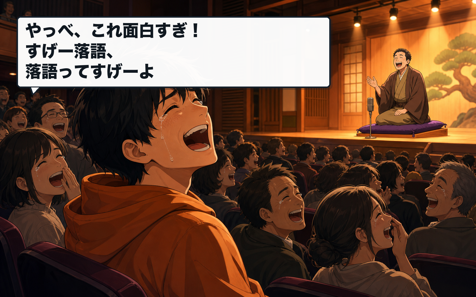 落語会場で多くの観客と涙を流して笑っている主人公。セリフ：やっべ、これ面白すぎ！すげー落語、落語ってすげーよ